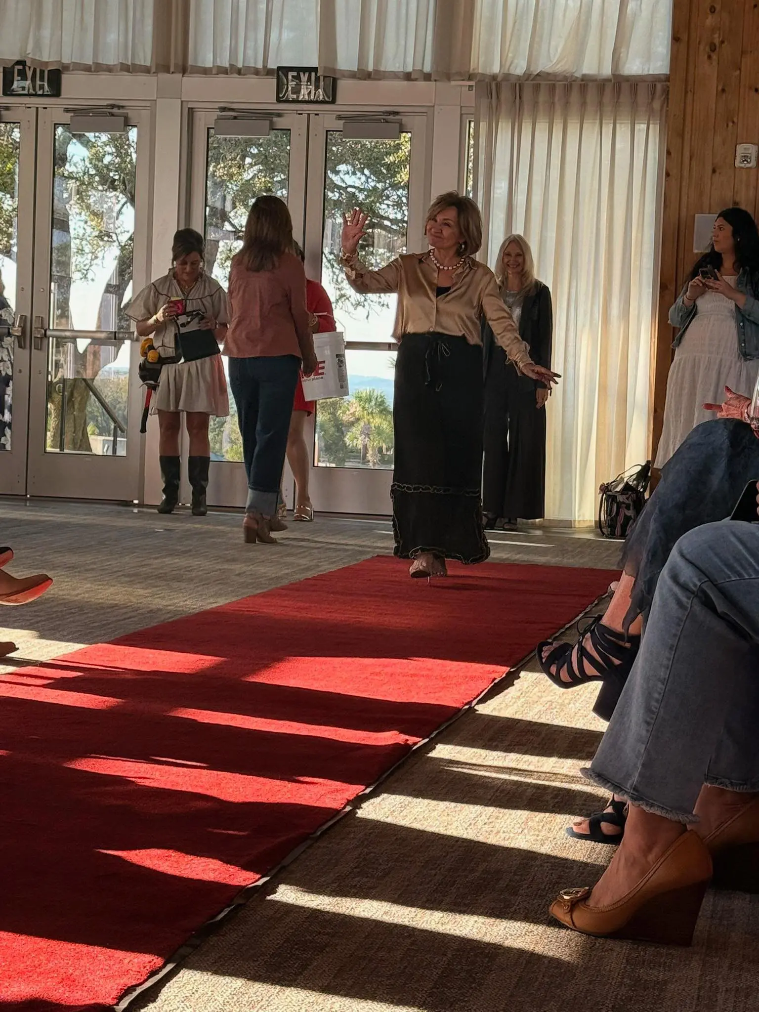 Woman waving on indoor red-carpet runway