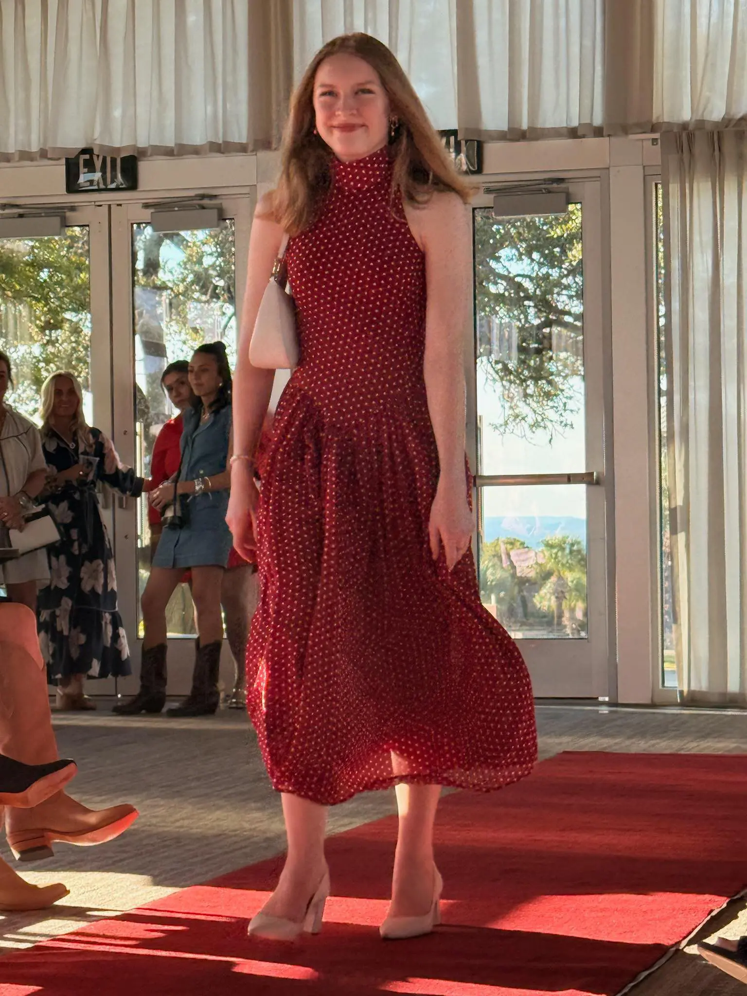 Woman modeling red polka-dot dress on runway