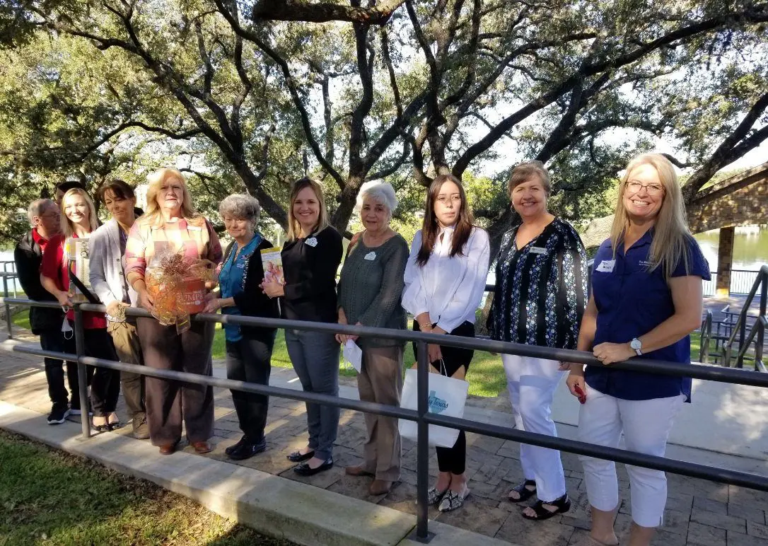 Group of women standing by railing under trees